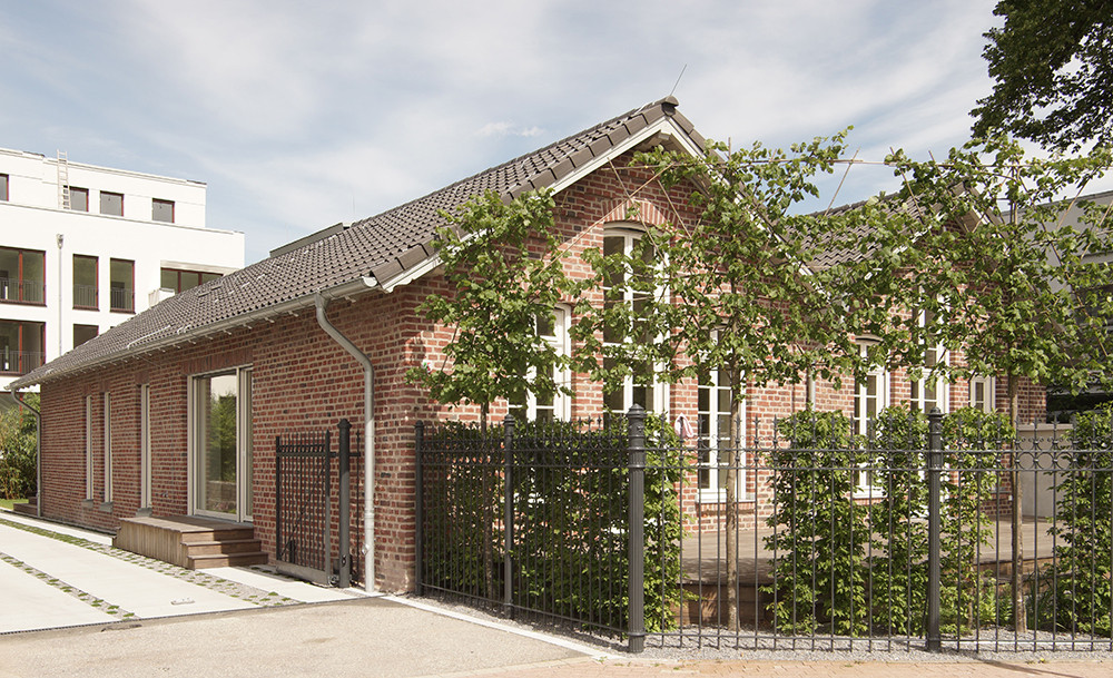 Das Bootshaus: ehemalige Lagerhalle aus rotem Backstein hinter dem historischen Zaun